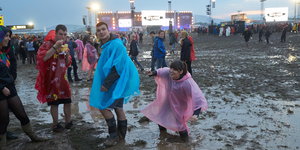 Festivalbesucher in Regenmänteln gehen beim Festival „Rock am Ring“ nach einem Gewitterregen über das aufgeweichte Gelände