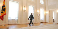 Joachim Gauck verlässt den Saal im Schloss Bellevue, an der Fensterfront enltanggehend. Links die Bundesflagge
