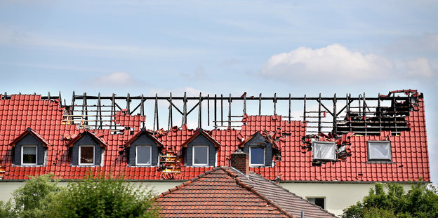 Der ausgebrannte Dachstuhl eines Hauses vor einem blauen Himmel.