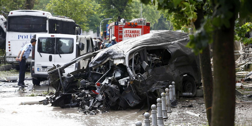 Das zerstörte Auto, in dem sich die Bombe befand, neben einem Polizeibus