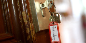 Ein Schlüssel mit Schlüsselanhänger auf dem "Ferienwohnungen" steht, steckt in einem Schloss