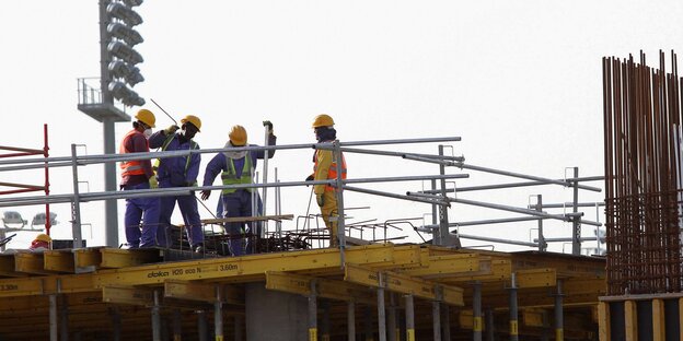Mehrere Arbeiter stehen auf einer Baustelle in Katar