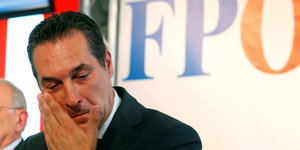 Mann mit roten Augen hält Hand an Wange, es ist FPÖ-Chef Strache