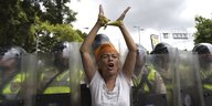 Eine Demonstrantin hebt die Hände, hinter ihr eine Reihe von Polizeischilden