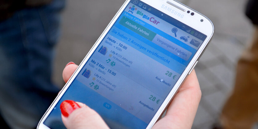 In einer Hand mit roten Fingernägeln liegt ein Handy, dessen Display eine Blablacarunterhaltung anzeigt