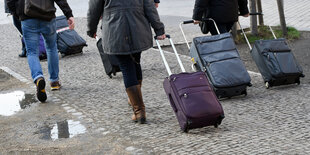 Laufende TouristInnen mit Rollkoffern