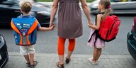 Mutter mit zwei Kinder an der Hand steht an der Straße
