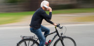 Ein Mann telefoniert auf dem Fahrrad