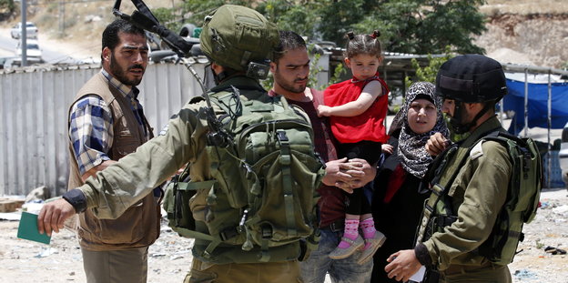 Zwei Soldaten sprechen mit einer Familie mit kleinen Kindern