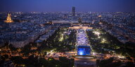 Luftaufnahme von Paris bei Nacht, links im Bild ist die hell erleuchtet Fanmeile