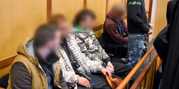 Vier junge Männer mit verpixelten Gesichtern sitzen auf einer Anklagebank, ein fünfter steht.