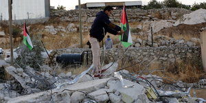 Ein Mann mit palästinensischer Fahne auf Trümmern