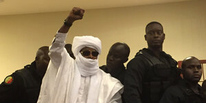 Hissène Habré, der frühere Diktator des Tschads, steht mit gereckter Faust in einem Gerichtssaal