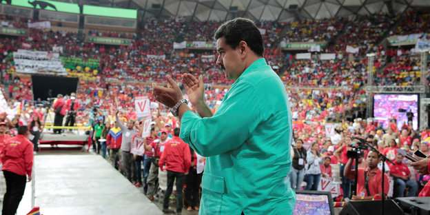 Ein Mann, Nicolas Maduro, klatscht in einer voll besetzten Halle