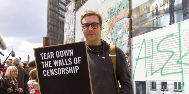 Mann mit Brille, es ist Jacob Appelbaum, mit einem Schild mit der Aufschrift "Tear down the walls of cenzorship"