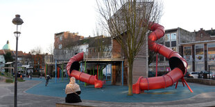 Frau sitzt an kargem Spielplatz