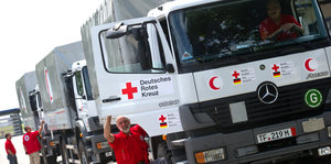 Mehrere Lastkraftwagen vom Deutschen Roten Kreuz fahren gerade los.