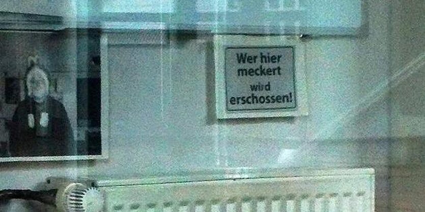 Ein Schild mit der Aufschrift: "Wer meckert, wird erschossen."