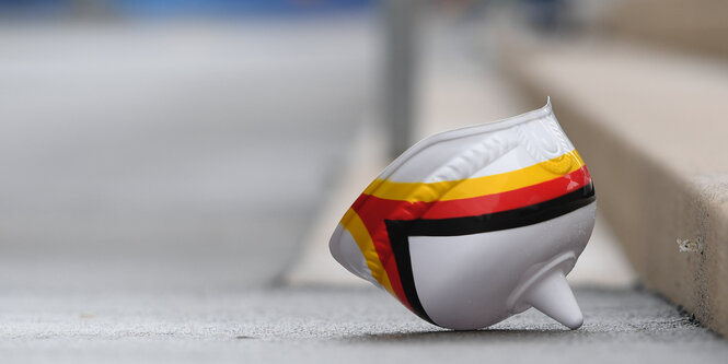 ein weißer Stahlhelm mit schwarz-rot-goldener Flagge drauf