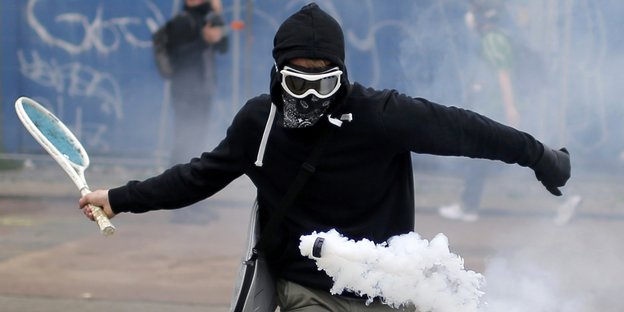 Demonstrant schlägt eine Gaskartusche der Polizei mit einem Tennisschläger zurück