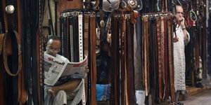 Ein Mann liest Zeitung zwischen Marktständen in Marrakesch