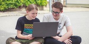 Zwei Jugendliche schauen auf ein Laptop