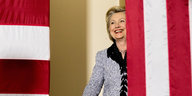 Hillary Clinton strahlt, im Vordergrund und Hintergrund Fahnen