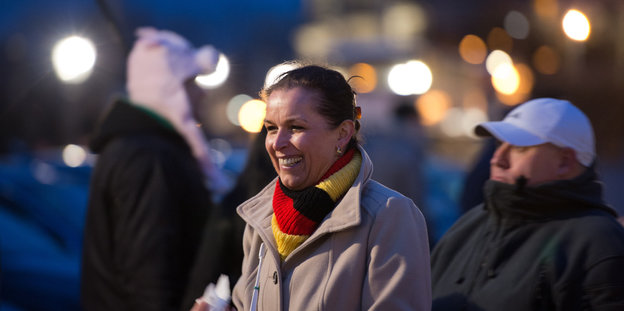 Tatjana Festerling lächelt vor einer Kundgebung und hat einen Deutschlandschal um