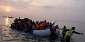 Menschen kommen in einem Boot an der Küste von Lesbos an