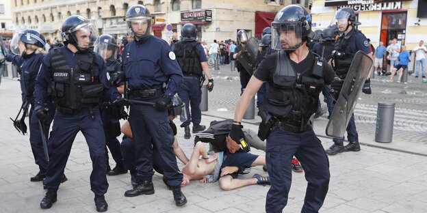 Polizisten in Kampfmontur in Marseille, im Hintergrund liegen Menschen am Boden