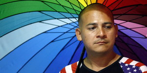 Ein Unterstützer der LGBTIQ-Community in Kolumbien ehrt die Opfer von Orlando und hält einen Schirm in Regenbogenfarben