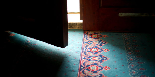 Eine Tür steht einen Spalt offen und zeigt einen orientalisch gemusterten Teppich