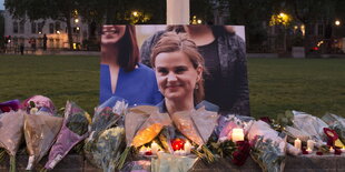 Blumen liegen vor einem Foto von Jo Cox vor einer Wiese