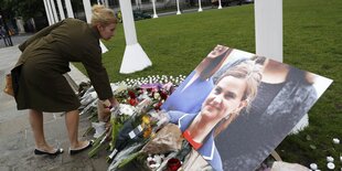 Eine Frau legt Blumen neben einem Bild von Jo Cox nieder