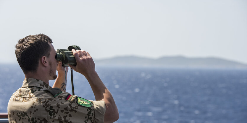 Soldat mit Feldstecher vor Meer und Küste