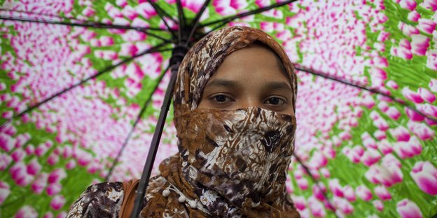 Frau mit Kopftuch und farbenfrohem Schirm