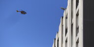 Ein Polizeihubschrauber fliegt am blauen Himmel auf einen Wohnhauskomplex zu