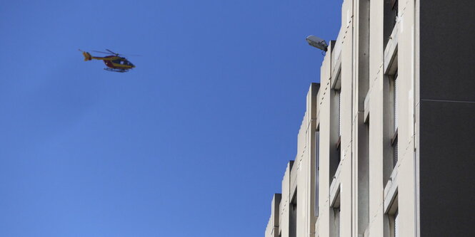 Ein Polizeihubschrauber fliegt am blauen Himmel auf einen Wohnhauskomplex zu