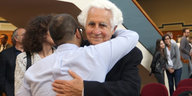 William Glied wird von seinem Enkel umarmt