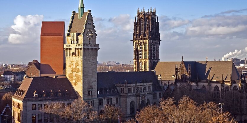 Duisburgs Rathaus im Vordergrund, im Hintergrund ein Kirchturm vor blauem Himmel