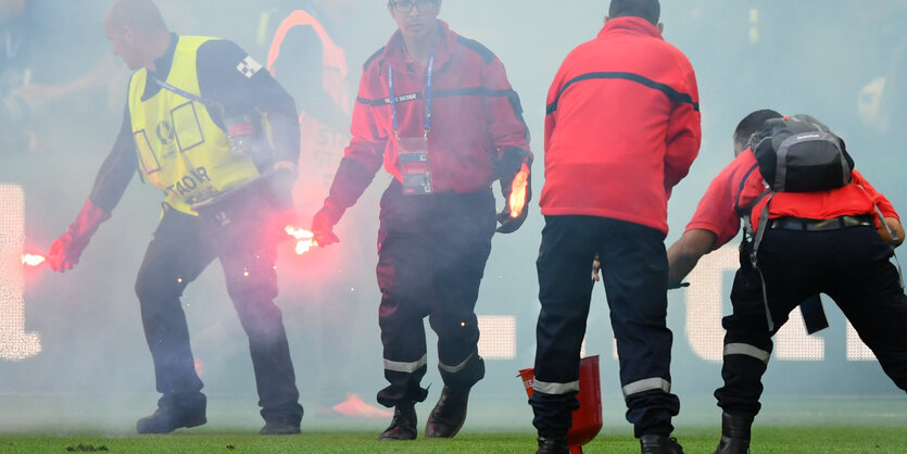 Ordner sammeln brennende Benaglos vom Fußballrasen ein