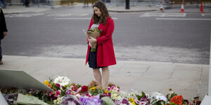 Frau im roten Mantel vor einem Blumenmeer am Rande des Parliament Square