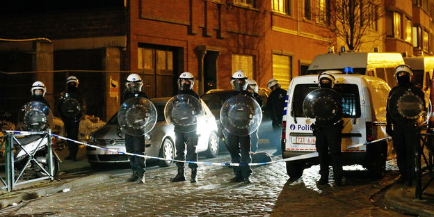 Eine Reihe von Polizsiten sperrt eine Straße im nächtlichen Belgien ab.