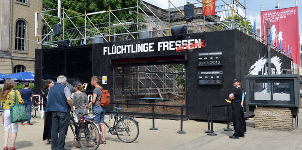 Besucher betrachten den Tigerkäfig vor dem Gorki-Theater in Berlin-Mitte, der zur Kunstaktion "Flüchtlinge fressen" gehört