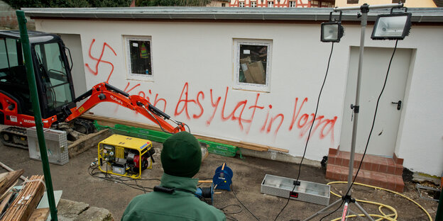 Ein Hakenkreuz und der Spruch "Kein Asylat in Vorra" stehen an einer Hauswand