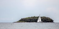 Ein Segelboot kreuzt vor einer Insel