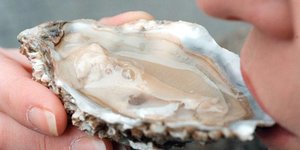 Ein Mensch schlürft eine Auster