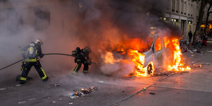 Feuerwehrleute im Einsatz an einem brennenden Auto