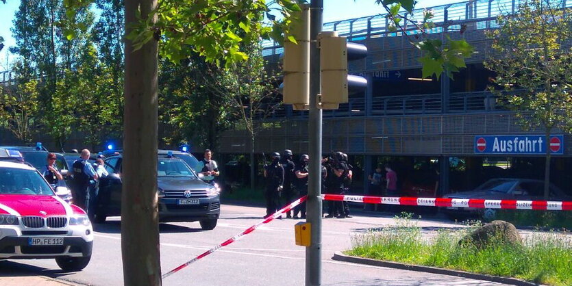 Polizeiautos stehen hinter Absperrband an einem Parkhaus