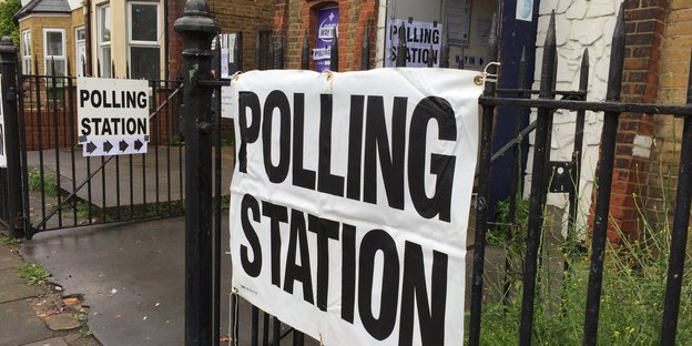 An einem Zaun hängt ein Schild „Polling Station“